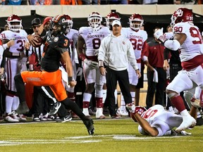 Oklahoma State Cowboys quarterback Spencer Sanders carries for a touchdown past Oklahoma Sooners defensive back Billy Bowman (5) and defensive lineman Josh Ellison during the second half of an NCAA college football game Saturday, Nov. 27, 2021, in Stillwater, Okla., on Nov. 27, 2021. The host Cowboys won 37-33.