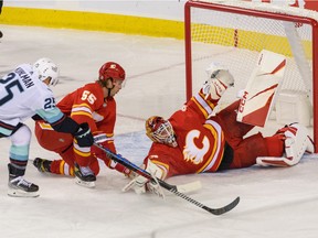 Le gardien des Flames de Calgary Jacob Markstrom effectue un arrêt contre l'attaquant du Kraken de Seattle Karson Kuhlman alors que Noah Hanifin défend au Scotiabank Saddledome de Calgary le lundi 3 octobre 2022.