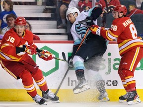 L'attaquant des Flames de Calgary Andrew Mangiapane et le défenseur Nikita Zadorov affrontent le centre du Seattle Kraken Shane Wright au Scotiabank Saddledome de Calgary le lundi 3 octobre 2022.