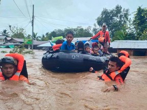 This handout photo taken and released by the Philippine Coast Guard on Friday, Oct. 28, 2022 shows rescue workers evacuating people from a flooded area due to heavy rain brought by Tropical Storm Nalgae in Parang, Maguindanao province.