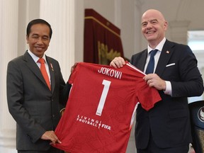 Indonesian President Joko Widodo holds a jersey with the FIFA President Gianni Infantino after their meeting at the palace in Jakarta, Indonesia, October 18, 2022, in this photo taken by Antara Foto.