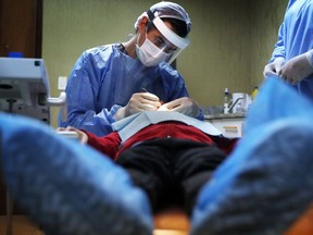 A dentist attends to a child at a family clinic in Asuncion, Paraguay, June 2, 2020. Health department officials say the federal government plans to hire a third-party company to process claims for its new dental-care insurance program.