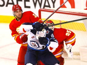 Calgary Flames defenceman Connor Mackey battles Winnipeg Jets forward Kyle Connor in front of goaltender Jacob Markstrom during a pre-season game at Scotiabank Saddledome in Calgary on Friday, Oct. 7, 2022.