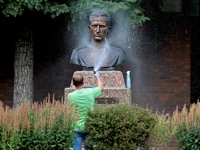 A volunteer washes spray paint off the Roman Shukhevych statue at the Ukrainian Youth Unity Complex, 9615 153 Ave., in Edmonton Tuesday Aug. 10, 2021.