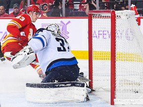 Adam Ruzicka # 63 des Flames de Calgary marque contre Conner Hellebuyck # 37 des Jets de Winnipeg lors de la première période d'un match de la LNH au Scotiabank Saddledome le 12 novembre 2022 à Calgary, Alberta, Canada.