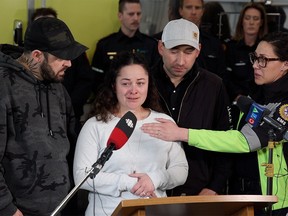 Airdrie paramedic Jayme Erickson is comforted by family, friends and coworkers while talking with media at a firehall in Airdrie on Tuesday, November 22, 2022. Erickson was at the scene of a serious car collision on November 15, and only found out later that the badly injured young woman she had cared for was her daughter Montana. Jayme was able to get to the hospital to be with Montana before she passed away.