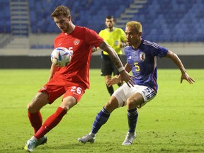 Canada’s Joel Waterman (left) controls the ball while being marked by Japan Yuto Nagatomo during a friendly at Al-Maktoum Stadium in Dubai on Nov.  17, 2022. Canada won 2-1.