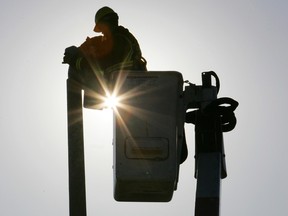 An Enmax employee rides a hydraulic lift as he checks streetlights along McCall Way N.E.