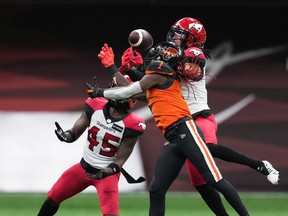 The B.C. Lions’ Lucky Whitehead, front, fails to make the reception as Calgary Stampeders’ Javien Elliott, back right, and Trumaine Washington defend at B.C. Place in Vancouver on Sept. 24, 2022. The Stampeders won this game 25-11 but lost the season series to the Lions 2-1.