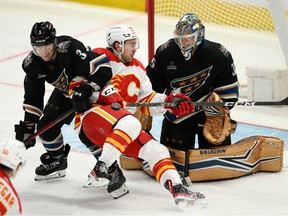 Calgary Flames forward Andrew Mangiapane battles with Washington Capitals defenceman Nick Jensen and goaltender Darcy Kuemper at Capital One Arena in Washington on Friday, Nov. 25, 2022.