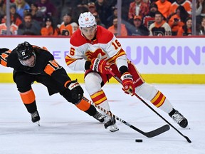 Calgary Flames defenceman Nikita Zadorov and Philadelphia Flyers forward Zack MacEwen reach for the puck at Wells Fargo Center in Philadelphia on Monday, Nov. 21, 2022.