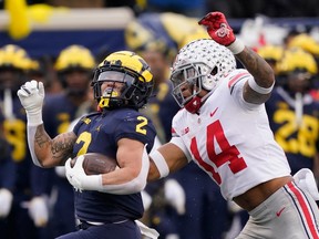 Michigan Wolverines running back Blake Corum is chased by Ohio State Buckeyes safety Ronnie Hickman at Michigan Stadium in Ann Arbor, Mich., on Nov.  27, 2021. Corum, a Heisman Trophy hopeful, could miss this year's installment of 'The Game' due to injury.