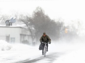 A man rides his bike down the street in Fort Erie, Ont., during an early winter storm that delivered high winds and large amounts of snow across southern Ontario and western New York, Nov. 19, 2022.
