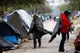 An asylum-seeking migrant walks covered with a blanket during a day of high winds and low temperatures at a makeshift encampment near the border between the U.S. and Mexico, after the U.S. Supreme Court allowed Title 42 to remain in place temporarily, in Matamoros, Mexico, on Dec. 23, 2022.