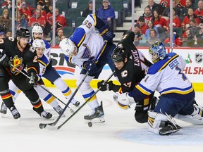 Calgary Flames forward Milan Lucic reaches for the puck with St. Louis Blues defenceman Colton Parayko and goaltender Thomas Greiss at the Scotiabank Saddledome in Calgary on Friday, Dec. 16, 2022.