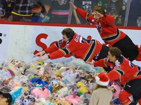Calgary Hitmen players Cael Zimmerman, top, Tyson Galloway and Adam Kidd dive into teddy bears after Zimmerman scored the Hitmen’s first goal against the Lethbridge Hurricanes during the annual Teddy Bear Toss game at the Scotiabank Saddledome on Dec. 4, 2021.