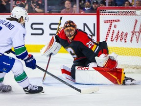 Dec 14, 2022; Calgary, Alberta, CAN; Calgary Flames goaltender Jacob Markstrom (25) makes a save against Vancouver Canucks right wing Conor Garland (8) during the overtime period at Scotiabank Saddledome. Mandatory Credit: Sergei Belski-USA TODAY Sports