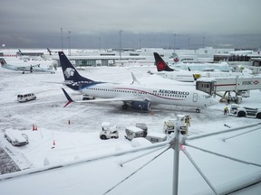 Aircraft are seen parked at gates at Vancouver International Airport after a snowstorm impaired operations leading to cancellations and major delays, in Richmond, B.C., on Tuesday, Dec. 20, 2022.