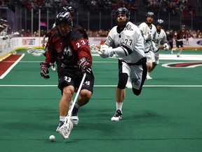 Jordan Gilles #23 of the Colorado Mammoth and Zach Currier #77 of the Calgary Roughnecks chase after a ground ball in the fourth quarter at Ball Arena on January 7, 2023 in Denver, Colorado.