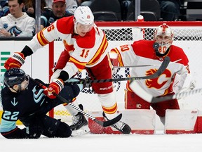 Calgary Flames goaltender Dan Vladar watches the puck as Flames defenceman Nikita Zadorov checks Seattle Kraken forward Oliver Bjorkstrand at Climate Pledge Arena in Seattle on Friday, Jan. 27, 2023.