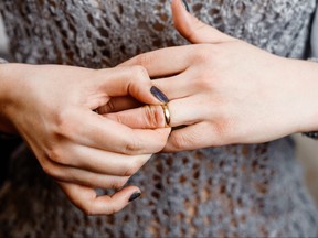 Closeup of womans hands, conflicted about taking off wedding band.