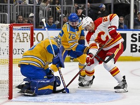 Flames forward Trevor Lewis battles for the puck in front of St. Louis Blues goaltender Jordan Binnington during the first period of Tuesday's game.