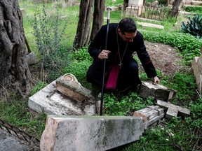 Archbishop Hosam Naoum inspects a vandalized tombstone at the Protestant Mount Zion Cemetery in Jerusalem January 4, 2023.