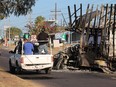 A vehicle passes by the burnt wreckage of a truck, which was set on fire by members of a drug gang in Culiacan, northwest of Mazatlan, Mexico, on Friday, Jan. 6.