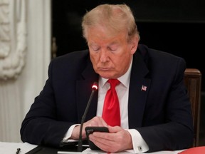 U.S. President Donald Trump uses a mobile phone during a roundtable discussion on the reopening of small businesses in the State Dining Room at the White House in Washington, D.C., June 18, 2020.