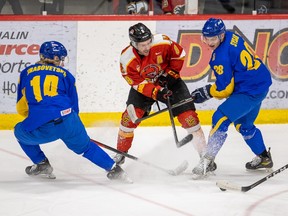Ukrainian U25 national team players Artem Hrabovetskyl (14) and Ivan Sysak battle for the puck with the Calgary Dinos’ Connor Gutenberg at Father David Bauer Arena in Calgary on Monday, Jan. 2, 2023.