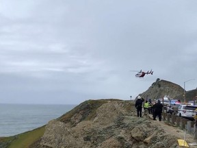 In this image from video provided by Cal Fire San Mateo, Santa Cruz Unit, emergency personnel respond to the scene after a Tesla plunged off a cliff along the Pacific Coast Highway, Monday, Jan. 2, 2023, in Northern California, near an area known as Devil's Slide, leaving four people in critical condition, a fire official said.