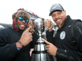 Nik Lewis, left, and Juwan Simpson are pictured with the Grey Cup in 2014 during their playing days with the Calgary Stampeders. Lewis is the club’s new receivers coach, while Simpson will guide the defensive line.