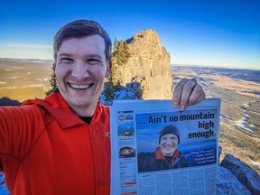 Jeromy Farkas holds a copy of the Calgary Sun atop Mount Yamnuska on Jan. 11, 2023. He is reassessing his plan to climb 25 peaks in 25 days due to the risk of avalanches in the backcountry.