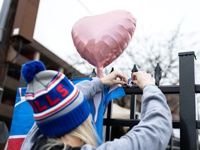 A football fan places a bracelet on the fence during a vigil outside University of Cincinnati Medical Center where Buffalo Bills safety Damar Hamlin is being treated after suffering a cardiac arrest during the January 2 National Football League (NFL) game against the Cincinnati Bengals.