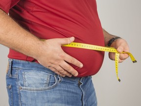 Overweight man measuring his waist.