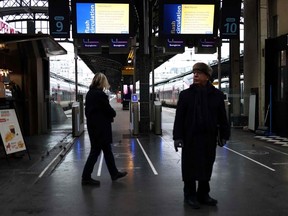 Passengers walk past a platform entrance with screens displaying a traffic alert message during a total traffic shutdown at the Gare de l'Est train station in Paris on January 24, 2023.