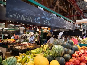 People shop for produce at the Granville Island Market in Vancouver, on Wednesday, July 20, 2022.