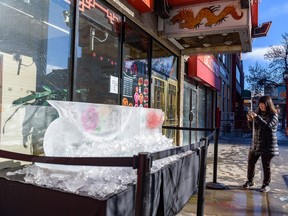Anissa Wong, secretary of the Chinatown BIA, takes a photo of remnants of the ice sculpture outside Silver Dragon restaurant in Chinatown after it was recently vandalized.