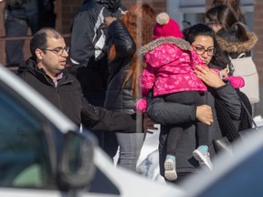 Parents wait for their children at the École du Parc meeting point after a city bus crashed into a Laval daycare on Feb. 8, 2023.