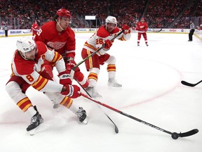 Calgary Flames defenceman Chris Tanev (8) and forward Elias Lindholm battle Detroit Red Wings forward Tyler Bertuzzi at Little Caesars Arena in Detroit on Thursday, Feb. 9, 2023.