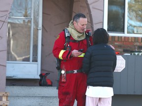 Calgary Firefighers and Police comfort and speak with a visitor at a fatal fire scene on Penworth Way SE in Calgary on Friday, February 17, 2023. A 71 year old man passed away at the scene, one of two fatal fires early on Friday.