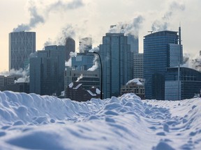 Steam rises from the downtown Calgary skyline framed by a snow filed street in Crescent Heights on Wednesday, Feb. 22, 2023.