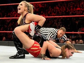 WWE superstar Natalya locks in her signature finisher, the Sharpshooter, during action against former MMA icon turned WWE star Ronda Rousey.