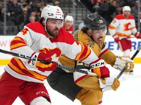 Feb 23, 2023; Las Vegas, Nevada, USA; Vegas Golden Knights center Chandler Stephenson (20) battles with Calgary Flames defenseman Rasmus Andersson (4) during the second period at T-Mobile Arena. Mandatory Credit: Stephen R. Sylvanie-USA TODAY Sports