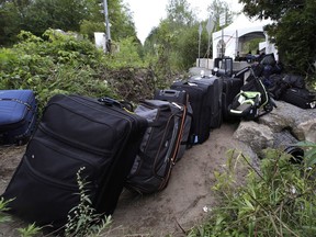 Luggage from migrants fills a pathway at an illegal crossing point from Champlain, N.Y., to Saint-Bernard-de-Lacolle, Que., Monday, Aug. 7, 2017. Quebec's immigration minister says she's surprised by reports that the City of New York is helping to provide free bus tickets to migrants heading north to claim asylum in Canada.