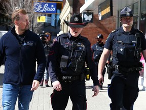 Minister of Public Safety and Emergency Services Mike Ellis (L) walks with a CPS member and an Alberta Sherriff on a tour of East Village and part of downtown Calgary on Thursday, March 23, 2023.