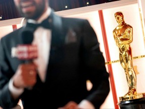 A member of the media speaks to a camera near a decorative Oscar statue as final preparations are made for the 95th Academy Awards, in Hollywood, Calif., Saturday, March 11, 2023.