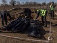 Police officers inspect exhumed bodies from the mass grave of three civilians killed at the time of the Russian occupation, at a cemetery in Borodyanka, near Kyiv, Ukraine, March 2, 2023.