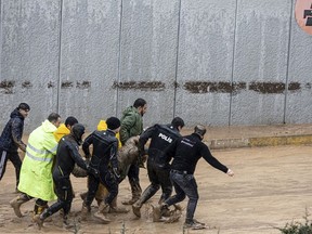 Police and rescue team members carry the body of a person during floods after heavy rains in Sanliurfa, Turkey, Wednesday, March 15, 2023.