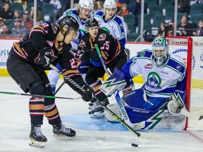 Calgary Hitmen-aanvaller Brandon Whynott probeert op zondag 5 maart 2023 een losse puck voorbij Swift Current Broncos-doelverdediger Reid Dyck te krijgen bij de Scotiabank Saddledome in Calgary.